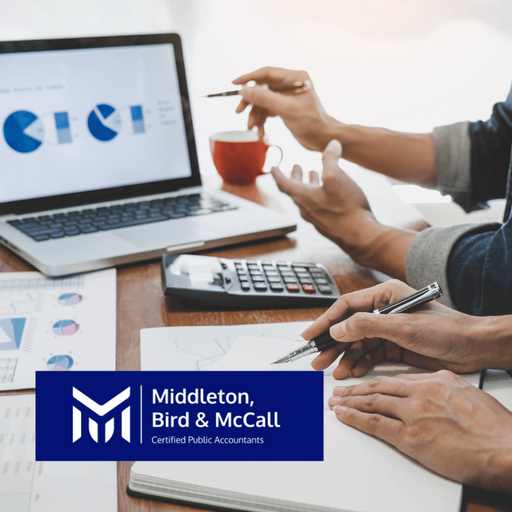 Close up of two sets of hands at a desk looking at numbers and balancing books.